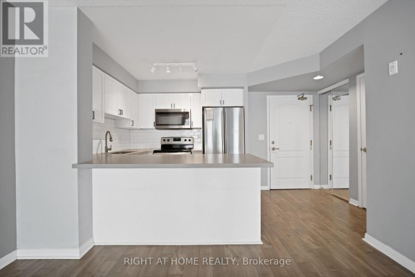 View of the kitchen island, entryway, and living space with hardwood floors. - 406 - 18 Stafford Street, Toronto