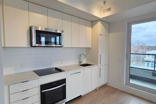 Modern kitchen with white cabinetry, stainless steel appliances, and a black stovetop. - 406 - 181 Sheppard Avenue E, Toronto