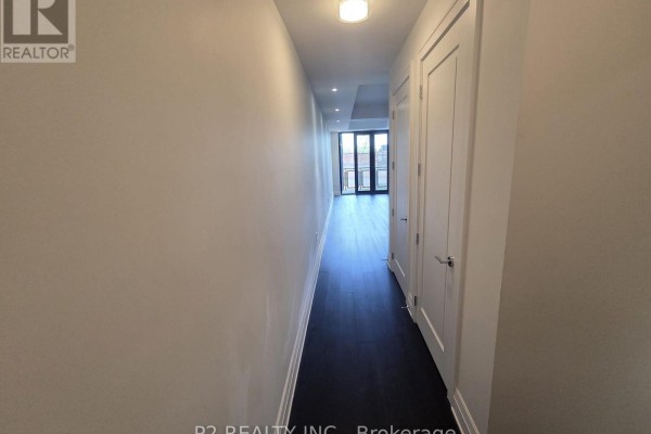 Spacious living area with white walls, dark hardwood floors, and balcony view. - 406 - 2 Forest Hill Road, Toronto