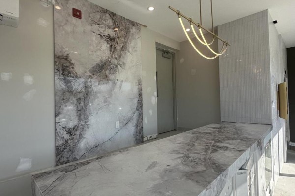 Lobby area with a marble front desk, modern wallpaper, and a decorative light fixture. - 406 - 49 Charles Street, Newmarket