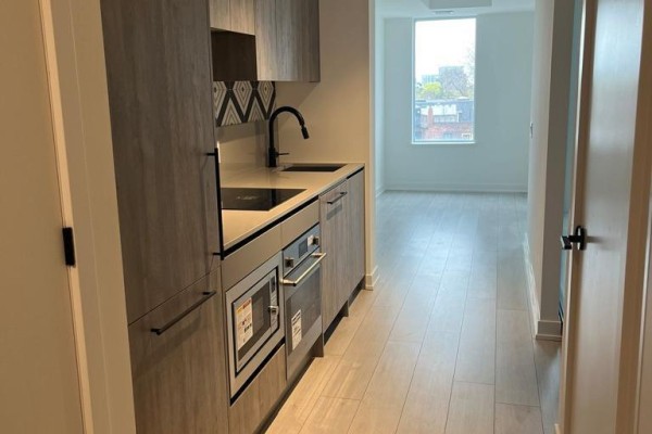 View from the hallway into the apartment kitchen and living space with a window. - 406 - 5 Lakeview Avenue, Toronto