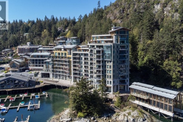 Close-up aerial view of the apartment building facade overlooking the marina with boats docked below. - 406 6707 Nelson Avenue, West Vancouver