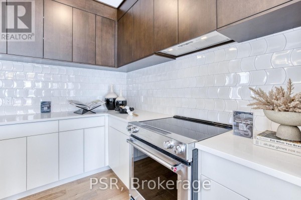 Kitchen corner with white quartz countertop, dark wood cabinets, stainless steel stove, and decorative items. - 406 Green Gate Boulevard, Cambridge