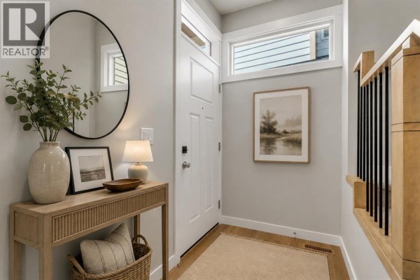 Foyer with a white front door, console table with decor, and a round mirror. - 406 South Shore Drive, Chestermere