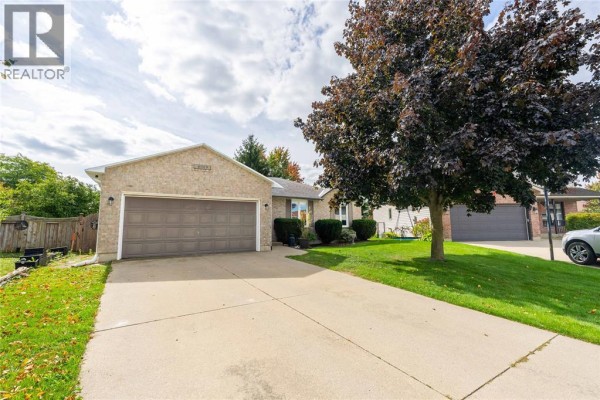 Side exterior view of a residential brick home with a two-car garage and a concrete driveway. - 4069 Pine Crescent, Petrolia