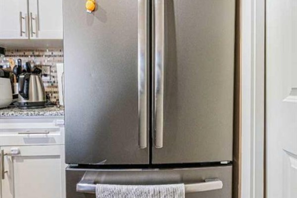 Close-up of a stainless steel French door refrigerator with silver handles in a kitchen. - 407, 10 Kincora Glen Park Nw, Calgary