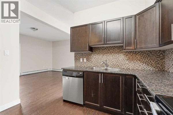Dining area with a round wooden table, four blue chairs, and a window overlooking the city. - 407, 4901 46 Street, Red Deer