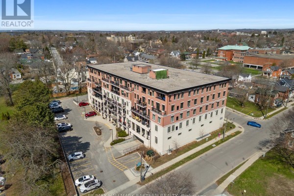 Aerial view of a brick apartment building with a parking lot and surrounding residential area. - #407 - 135 Orr Street, Cobourg