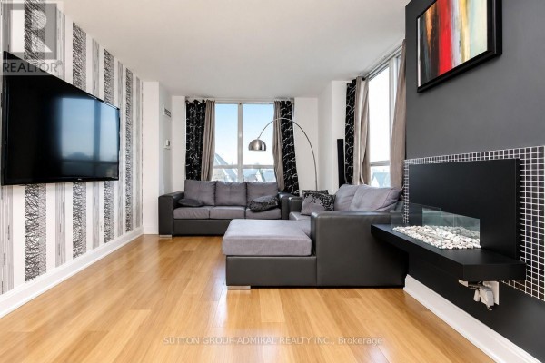 Building lounge area with sofas, chairs, a stone fireplace, and large windows. - 407 - 30 North Park Road, Vaughan