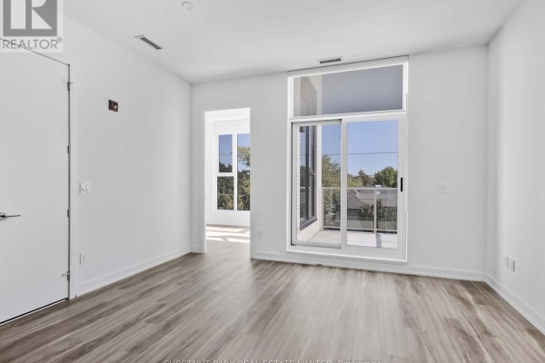 Bright room with light wood floors, white walls, and a sliding glass door. - 407 - 722 Marlee Avenue, Toronto