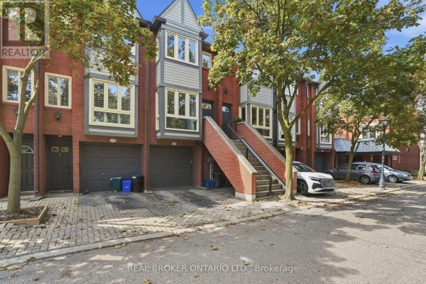 A row of townhouses with brick facades, multi-level windows, garages, and a central set of stairs. - 407 - 895 Maple Avenue, Burlington