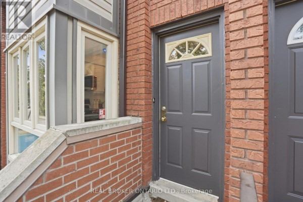 Front door of a townhouse with arched glass and a red brick surround, next to a bay window. - 407 - 895 Maple Avenue, Burlington