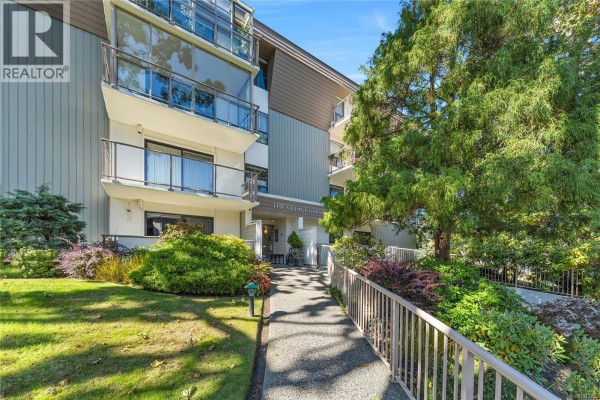 Pathway leading to the entrance of a building with trees and landscaping. - 407 2125 Oak Bay Ave, Oak Bay
