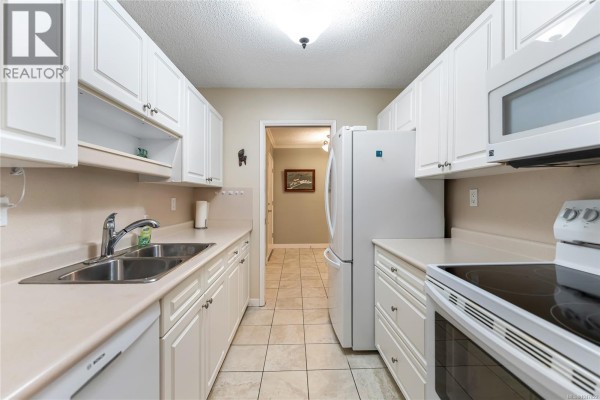 Kitchen with white cabinets, a double sink, and white appliances. - 407 2125 Oak Bay Ave, Oak Bay