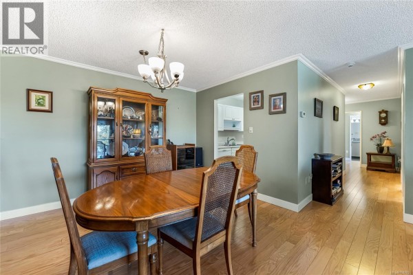 Dining room with a wooden table, chairs, and a china cabinet. - 407 2125 Oak Bay Ave, Oak Bay