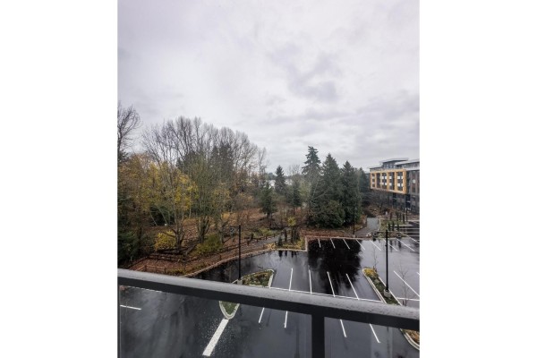 View from balcony of a parking lot, trees, and apartment buildings under a cloudy sky. - 407 27215 Aldergrove Town Centre Drive, Langley