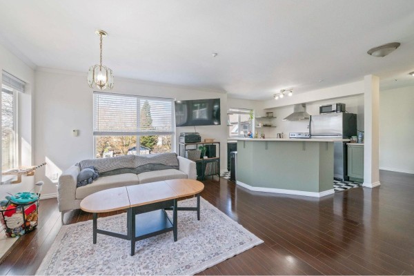 Living room and kitchen area with a sofa, fireplace, kitchen island, and stainless steel appliances. - 407 33407 Tessaro Crescent, Abbotsford