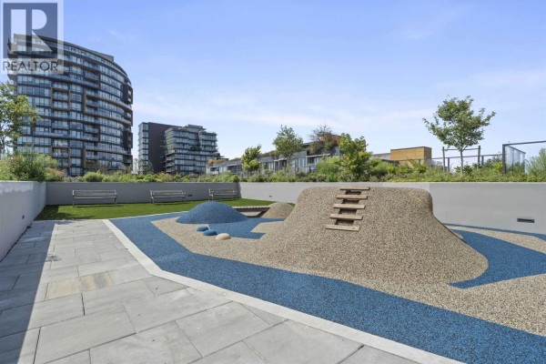 Outdoor children's play area with artificial turf, climbing structures, benches, and paved walkways. - 407 8415 Granville Street, Vancouver