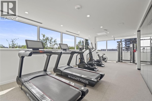 Fitness room with treadmills, elliptical machines, exercise bikes, and large windows overlooking the city. - 407 8415 Granville Street, Vancouver