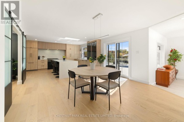 Modern kitchen and dining area with island, skylight, and sliding doors - 407 County Road 4 Prince Edward County