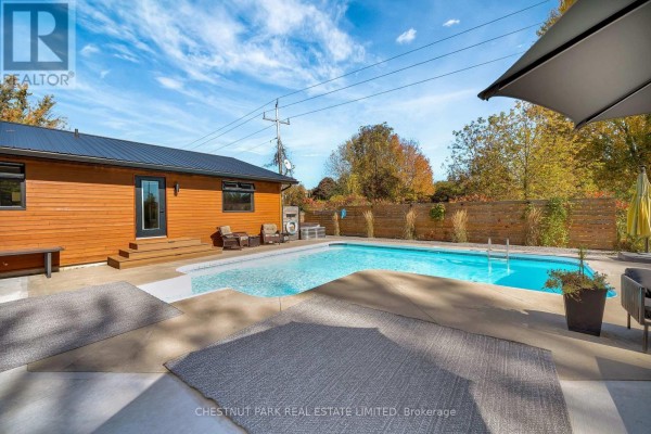 Swimming pool with patio, outdoor furniture, umbrella, and modern fence - 407 County Road 4 Prince Edward County