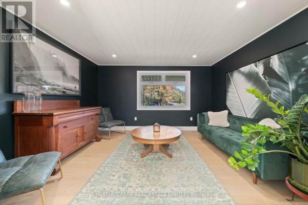 Green velvet sofa, wooden buffet, coffee table, and artwork in living room - 407 County Road 4 Prince Edward County