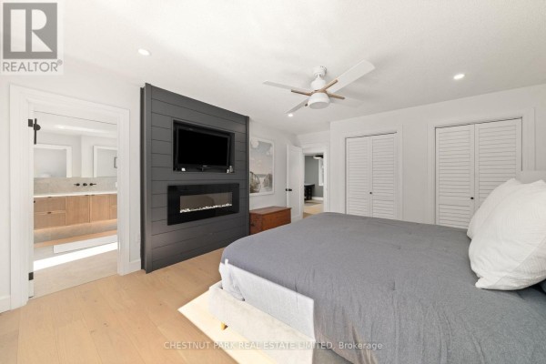 Bedroom with TV, fireplace, ceiling fan, and en-suite access - 407 County Road 4 Prince Edward County