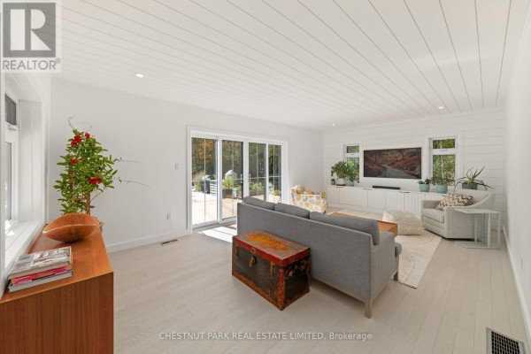 Living room with shiplap wall, entertainment center, sofa, armchairs, trunk coffee table, and sliding doors - 407 County Road 4 Prince Edward County