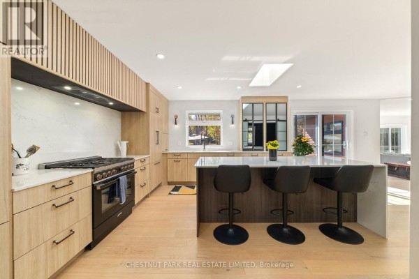 Modern kitchen island, bar stools, gas range, skylight, and wood cabinets - 407 County Road 4 Prince Edward County