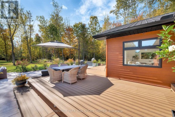 Outdoor dining set and umbrella on a wood deck with forest views - 407 County Road 4 Prince Edward County
