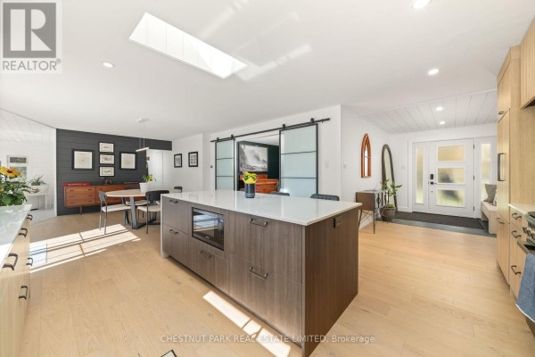 Modern kitchen island with built-in microwave, skylight, and barn doors - 407 County Road 4 Prince Edward County