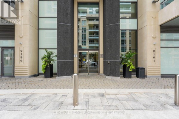 Close-up of the building entrance with glass doors, planters, and numbered signage. - 407 Se - 9199 Yonge Street, Richmond Hill