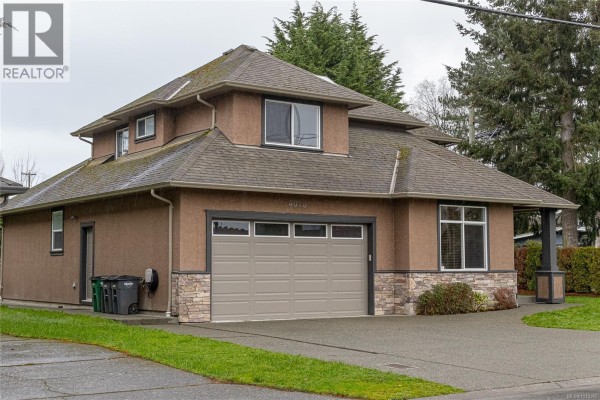 Side view of the house on a cloudy day, highlighting the garage and exterior materials. - 4073 Longview Dr, Saanich