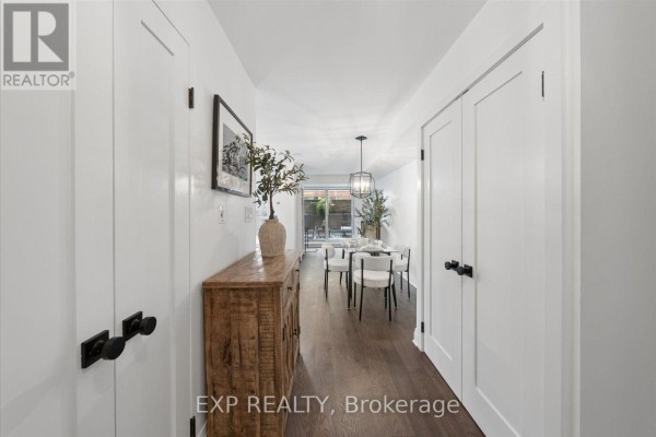 Hallway with white doors, a wooden console table, and a glimpse of a dining area beyond. - 408 - 230 King Street E, Toronto