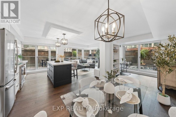Open-concept living, dining, and kitchen area with dark wood floors, island, and sliding glass doors. - 408 - 230 King Street E, Toronto
