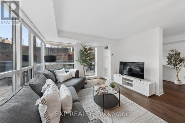 Living room with a large sectional sofa, coffee table, entertainment unit, and large windows. - 408 - 230 King Street E, Toronto
