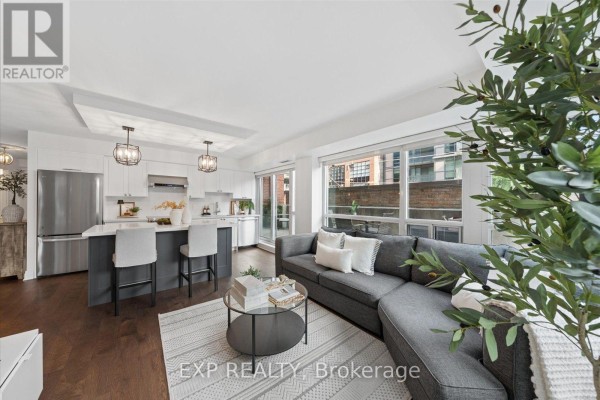 View from the living room towards the kitchen island and dining area with floor-to-ceiling windows. - 408 - 230 King Street E, Toronto