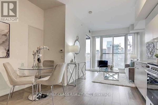 Dining area with a glass table and four grey chairs, adjacent to the living room. - 408 - 251 Jarvis Street, Toronto