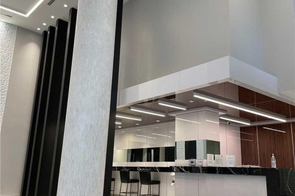 Contemporary building entrance with dark wood accents, a white reception desk, and modern lighting. - 408 - 32 Forest Manor Road, Toronto