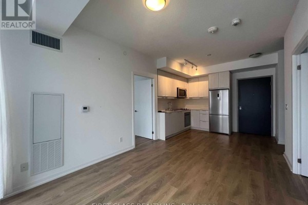 Open-concept living area and kitchen with light wood floors and stainless steel appliances. - 408 - 32 Forest Manor Road, Toronto