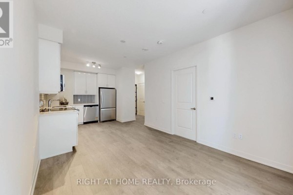 View of the kitchen area and entryway with light wood laminate flooring. - 408 - 38 Annie Craig Drive, Toronto