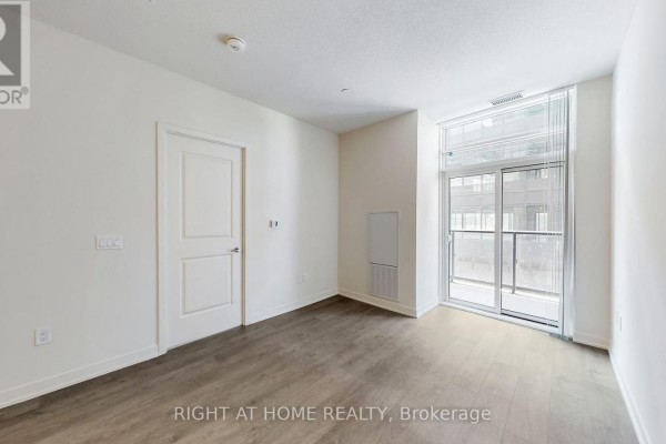 Living area with a closed door, vent, and a sliding glass door to a balcony. - 408 - 38 Annie Craig Drive, Toronto