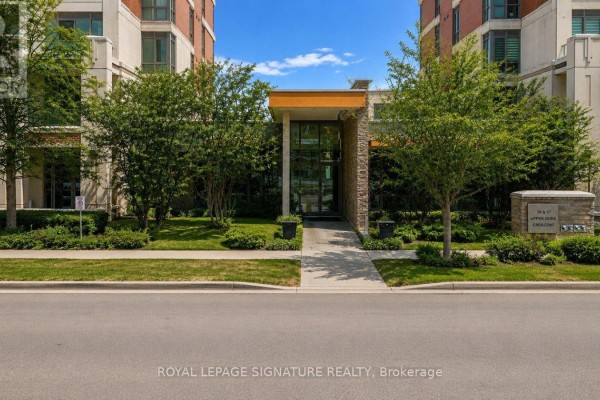 Living area of an apartment with dark wood floors, white walls, and a view into the kitchen and hallway. - 408 - 39 Upper Duke Crescent, Markham