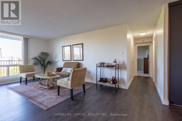 Living room with beige chairs, sofa, bar cart, and hallway leading to other rooms. - 408 - 665 Bathgate Drive, Ottawa