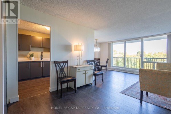 View from living area showing dining table and kitchen entrance with dark cabinets. - 408 - 665 Bathgate Drive, Ottawa