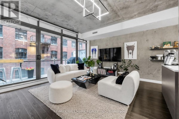 Living room with concrete ceilings, large windows, modern white furniture, and a balcony view. - 408 - 90 Broadview Avenue, Toronto