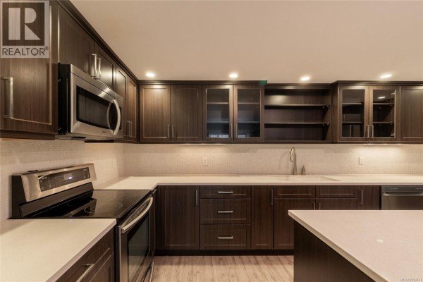 Close-up of kitchen featuring dark cabinets, stainless steel microwave, and quartz countertops. - 408 1005 Mckenzie Ave, Saanich