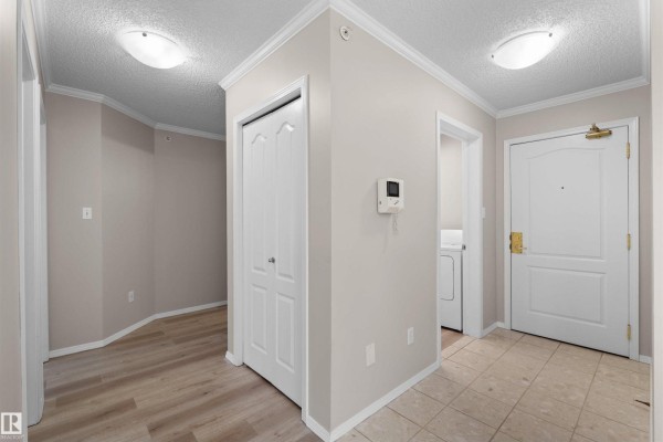 Interior hallway with beige walls, tile flooring, and closet doors. - #408 10610 76 St Nw, Edmonton
