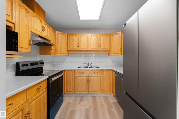 Kitchen with light wood cabinets, white countertops, and stainless steel appliances. - #408 10610 76 St Nw, Edmonton