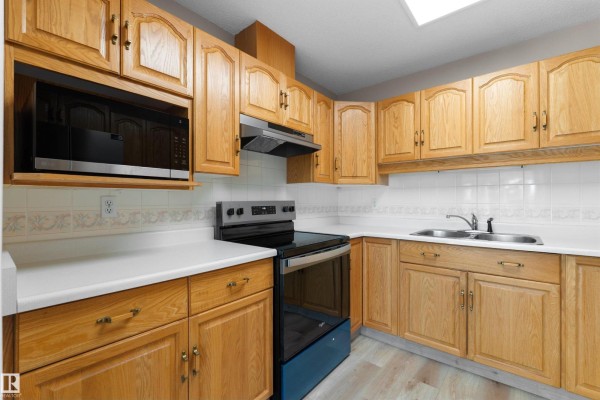 Another view of the kitchen showing oak cabinets, white backsplash, and a sink. - #408 10610 76 St Nw, Edmonton
